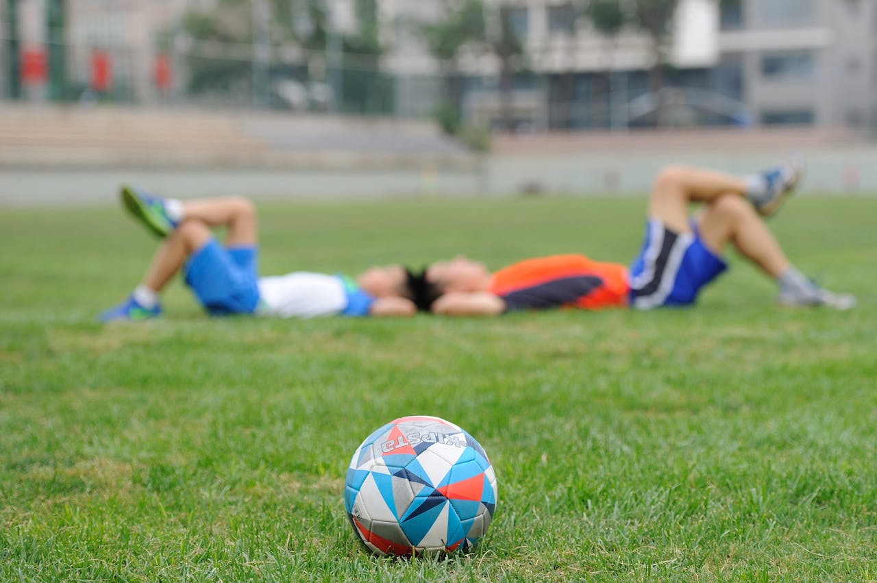 Crafting Captivating Headlines: Your awesome post title goes here Two teenagers lying on grass near a soccer ball, enjoying leisure time outdoors.